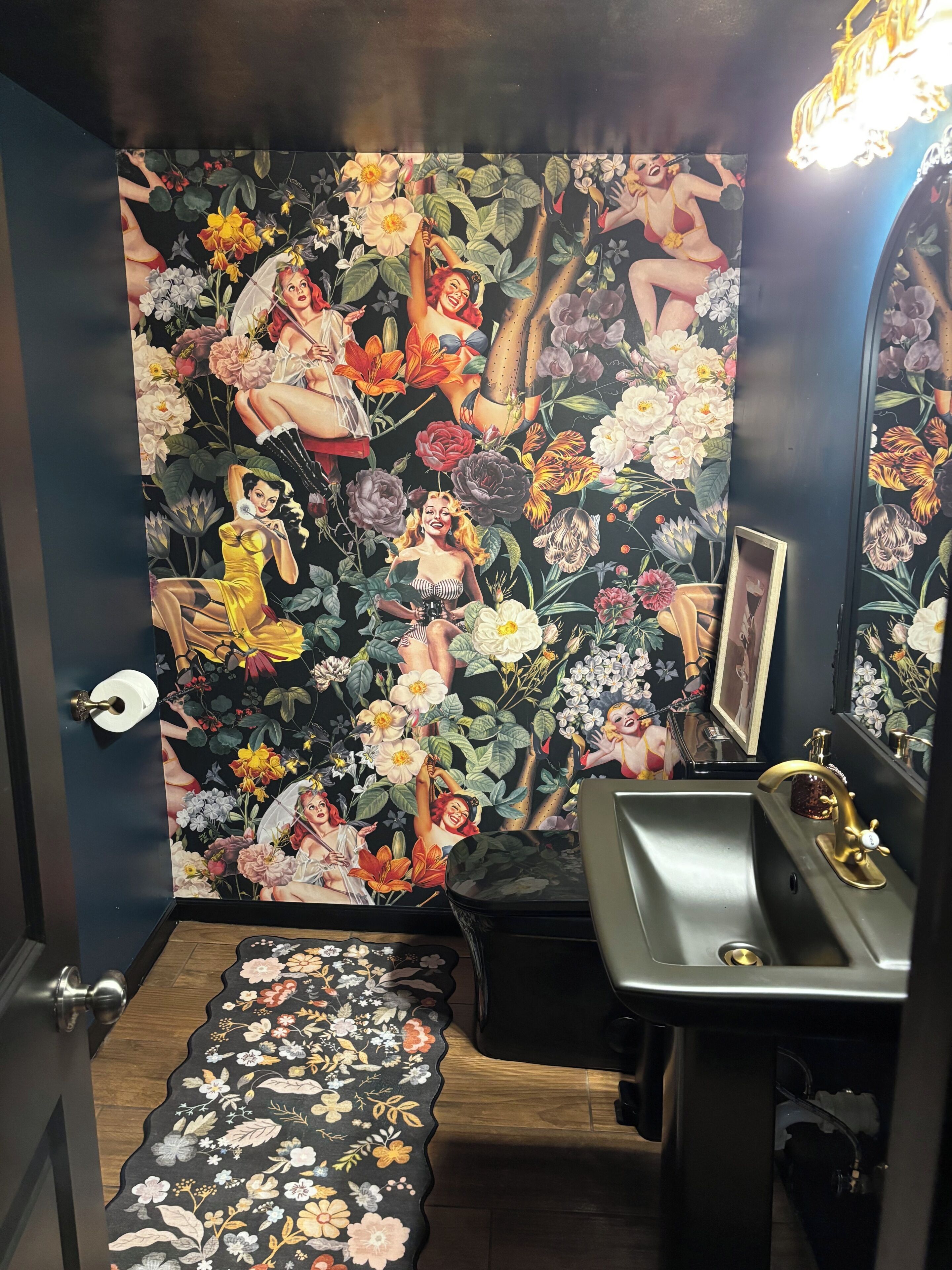 A bathroom with a floral wallpaper, a sink, and a mirror.