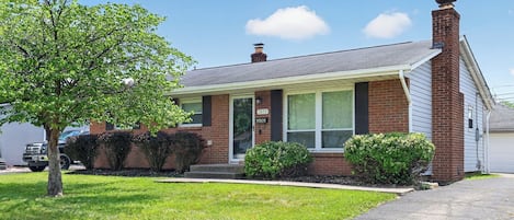 A single-story house with a brick facade, a front porch, and a garage.