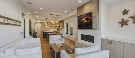A modern living room with a sofa set, a coffee table, and a TV mounted on the wall.