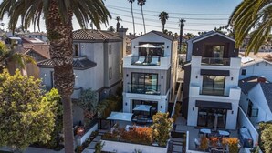 Un immeuble résidentiel moderne à plusieurs étages, doté de balcons, d’un espace extérieur aménagé pour s’asseoir et d’un jardin bien entretenu.