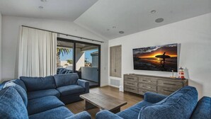 Un salon moderne avec un canapé, une table basse et un tableau représentant un coucher de soleil.