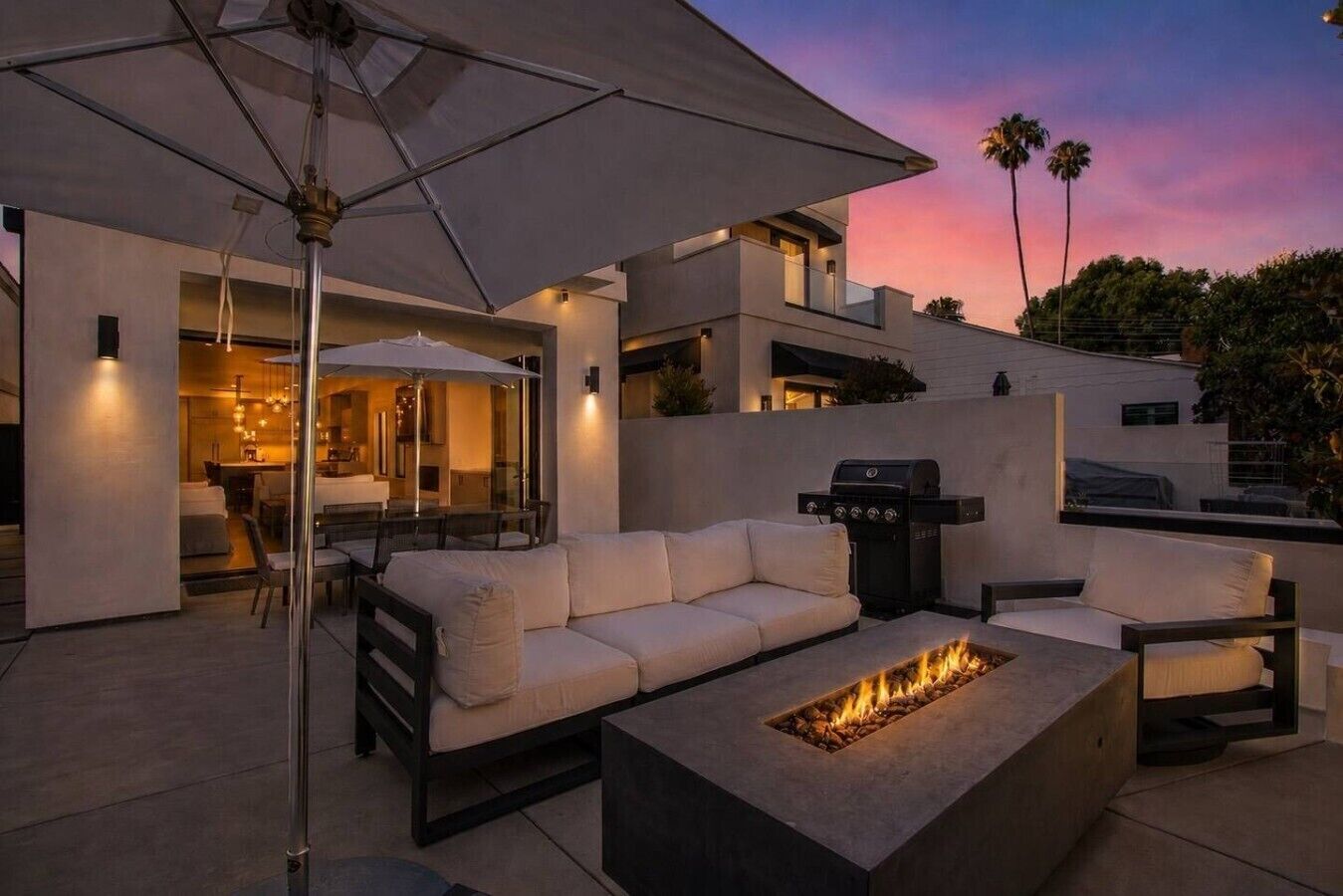 An outdoor patio with a fire pit, seating, and a grill.