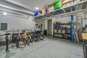 A bike storage area with bicycles, shelves with storage boxes, and a door leading to another room.