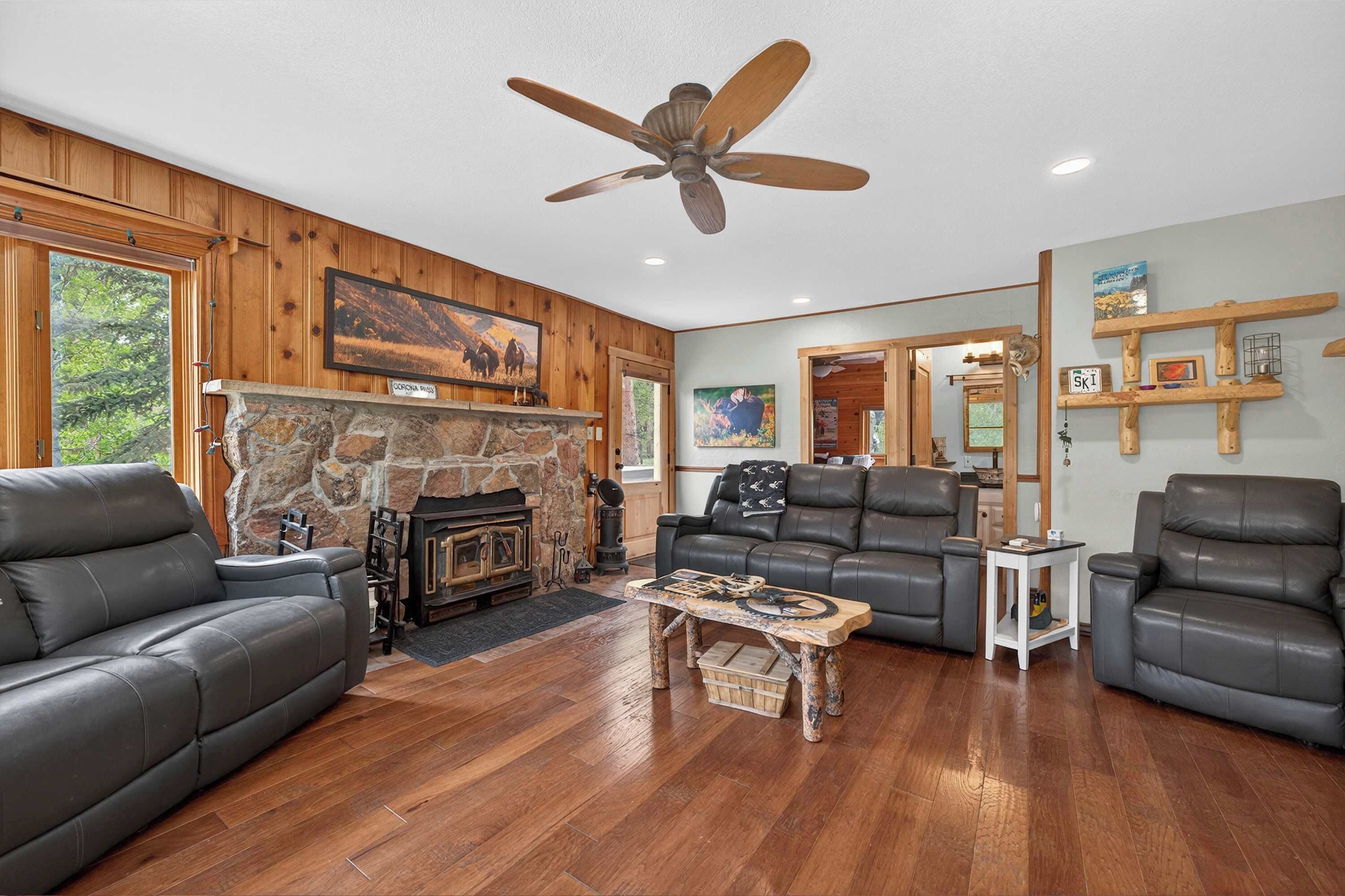 A spacious living room with a stone fireplace, leather sofas, and a wooden coffee table.