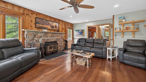 A spacious living room with a stone fireplace, leather sofas, and a wooden coffee table. - Charming 3 Bed Cabin| Lakes, Hiking, Hot Tub (Grand Lake)
