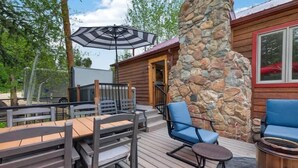 An outdoor deck with wooden furniture, a stone pillar, and a covered seating area. - Charming 3 Bed Cabin| Lakes, Hiking, Hot Tub (Grand Lake)