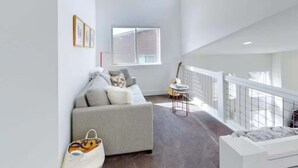 Una sala moderna con un sofá gris, una mesita y un ventanal.