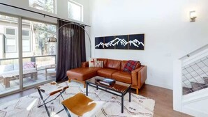 Una sala de estar moderna con un sofá de cuero, una mesita de centro y un ventanal grande.