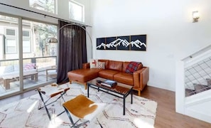 A modern living room with a leather sofa, a coffee table, and a large window. - Luxury Winter Park Condo| 2 Bed/ 2 Bath (Fraser)