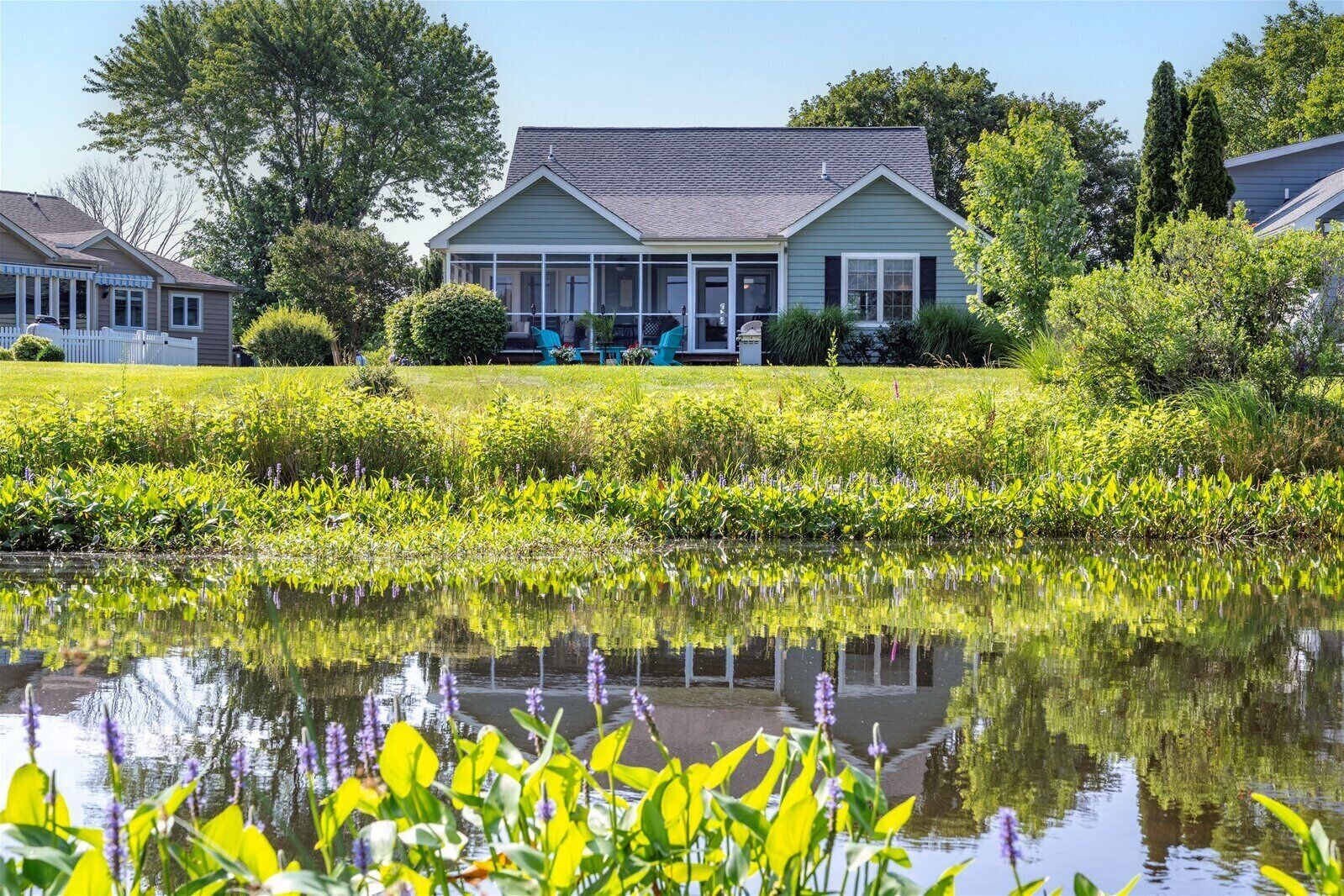 A house with a covered porch and a pond in front.