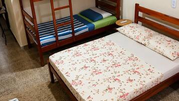 Ein Zimmer mit Etagenbett, einem Einzelbett, einem kleinen Tisch und einem Kühlschrank.