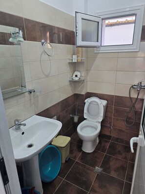Un baño con lavamanos, inodoro, ducha y ventana.
