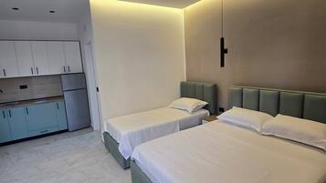 Un dormitorio moderno con dos camas, una kitchenette pequeña y una lámpara en el techo.