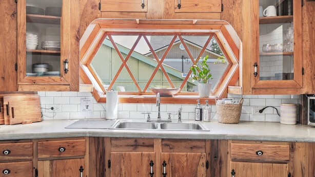 Eine Küche mit Holzausstattung, einem Doppelbecken und einem Fenster mit geometrischem Muster.