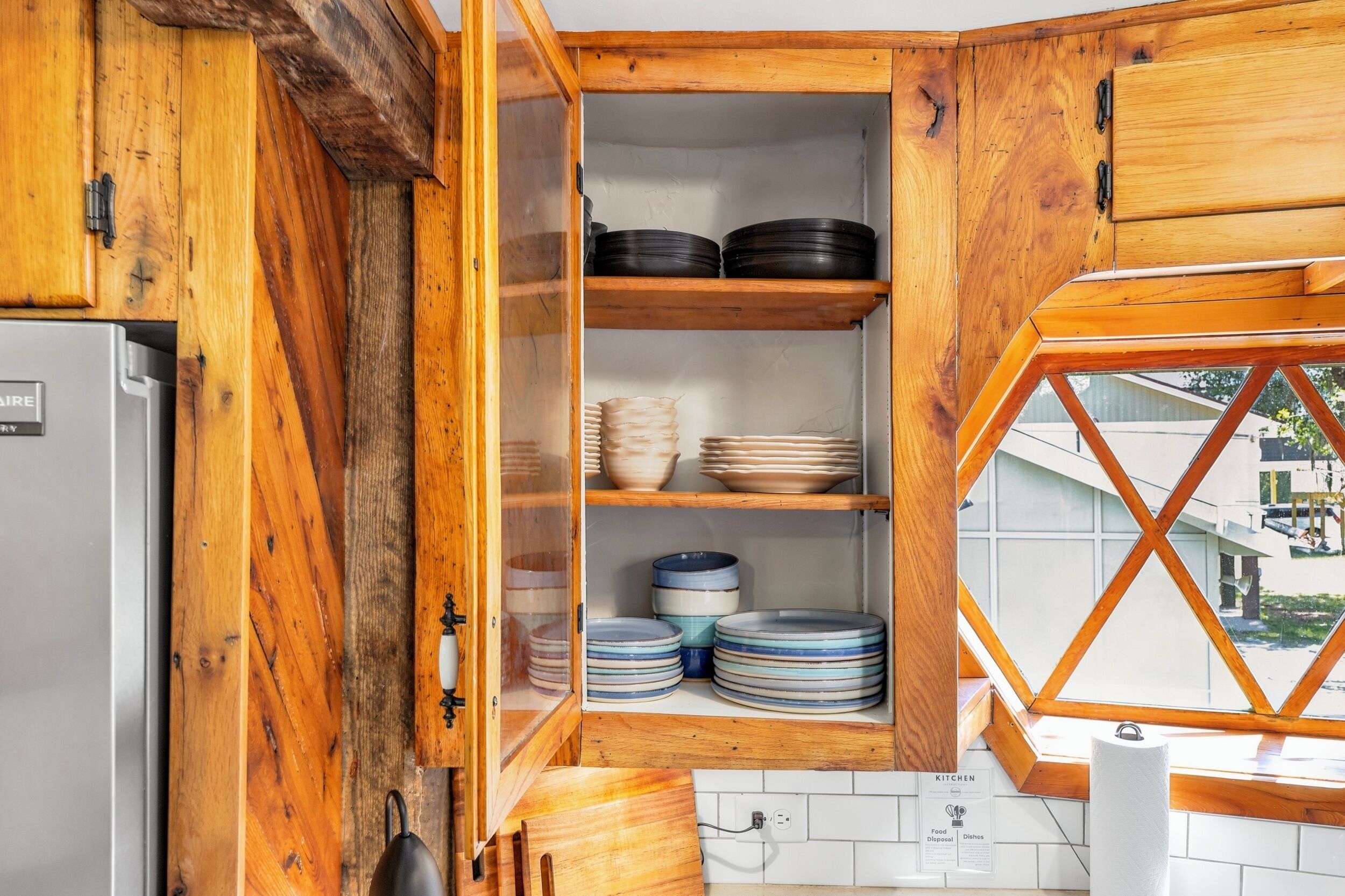 Une cuisine avec des meubles de rangement en bois, un réfrigérateur et une fenêtre donnant sur un beau paysage.