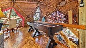 Ein Holzinterieur mit Billardtisch, Sitzecke und großen Fenstern.