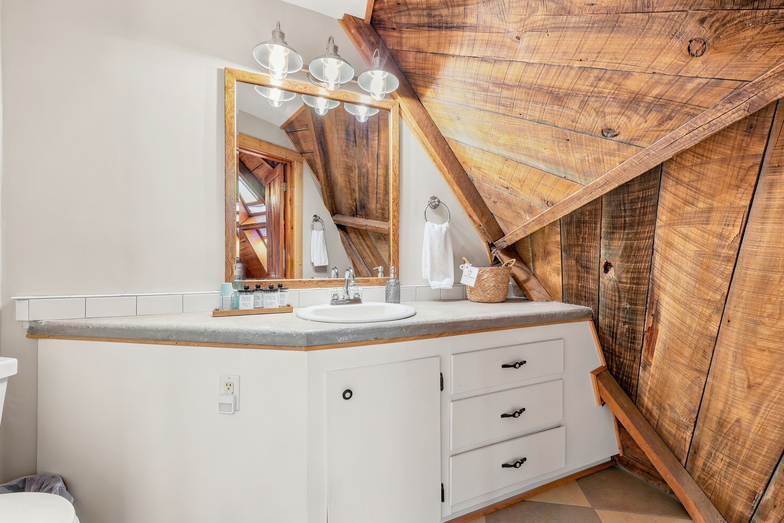 A bathroom with a wooden slat wall, a white vanity with a sink, and a mirror.