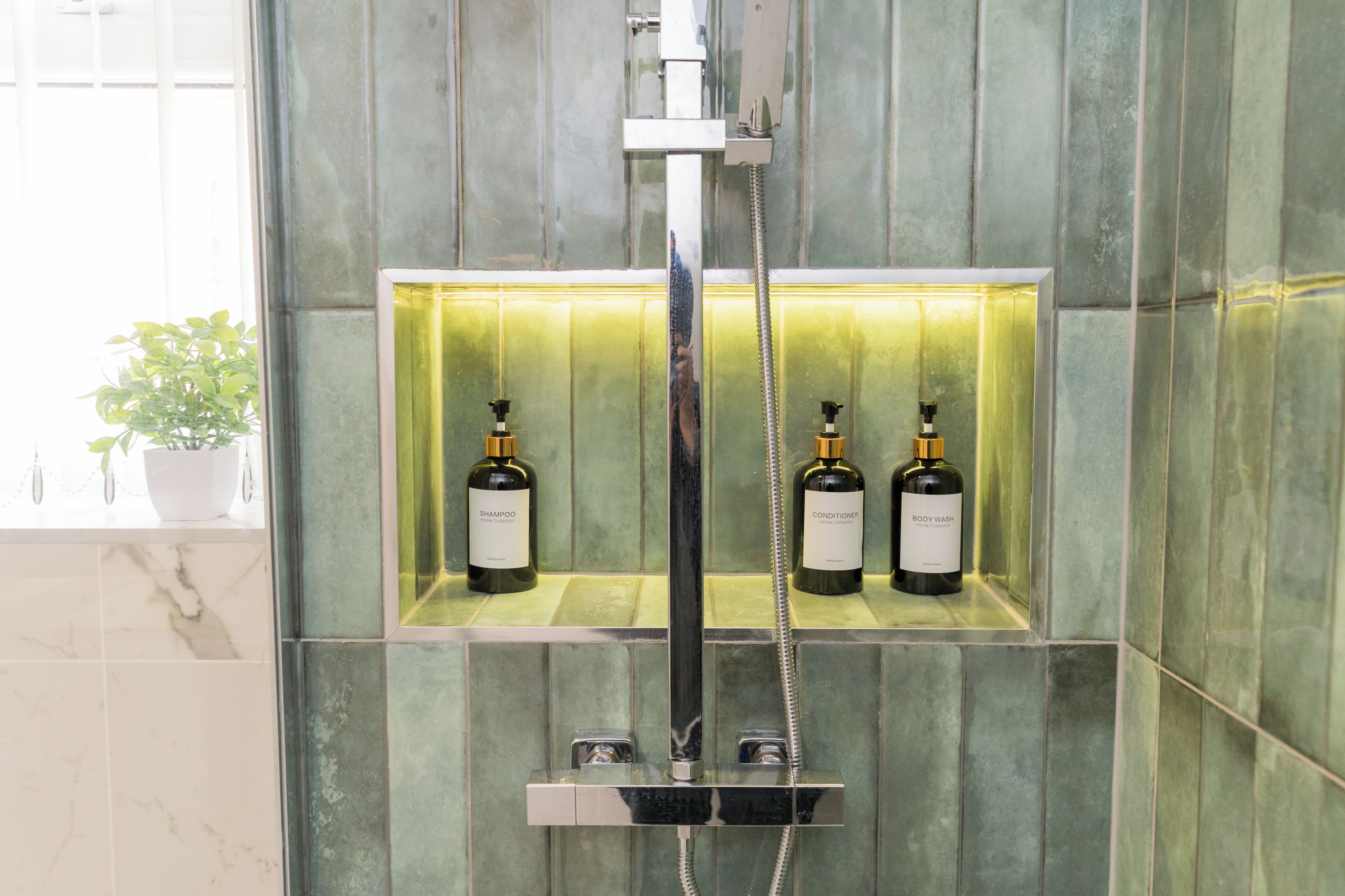 Ein Badezimmer mit Dusche, zwei Shampooflaschen und einer Pflanze im Topf.
