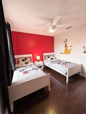 A room with two beds, a ceiling fan, and a Mickey Mouse wall decal. - 3BD 3BR Stylish Disney Retreat 15 Mins to Disney (Kissimmee)