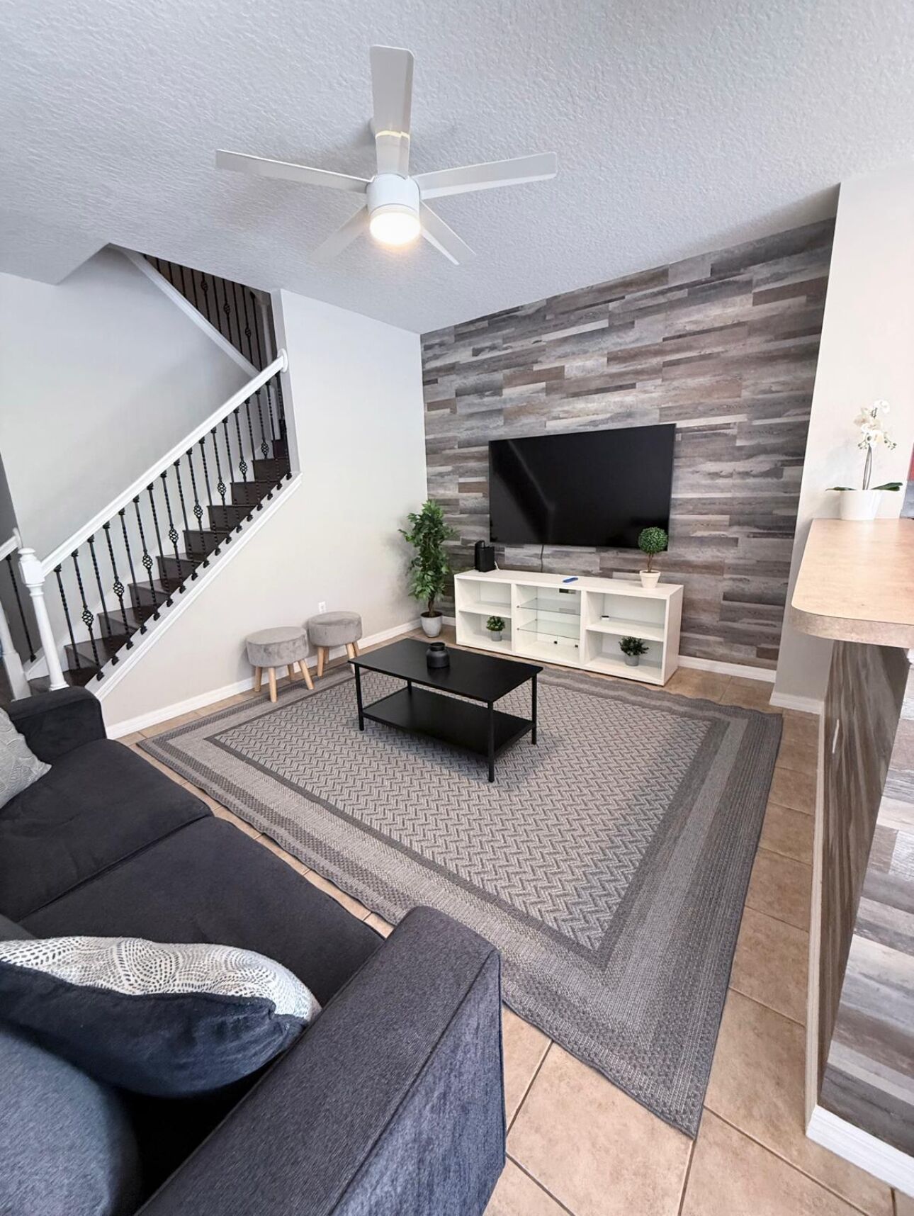 A living room with a sofa, coffee table, TV, and a staircase.