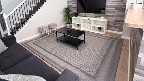 Una sala de estar con sofá, mesa de centro, televisor y una escalera.