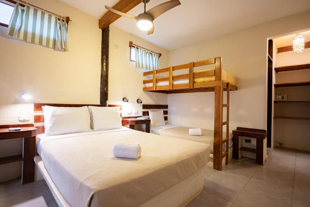 A hotel room with a bunk bed, a desk, a chair, a bedside table, and a ceiling fan.