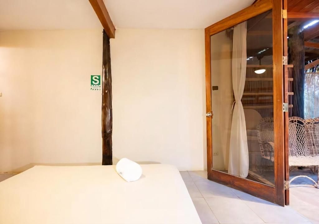 A room with a bed, a sliding glass door leading to a balcony, and a small sign on the wall.
