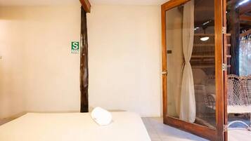 A room with a bed, a sliding glass door leading to a balcony, and a small sign on the wall.