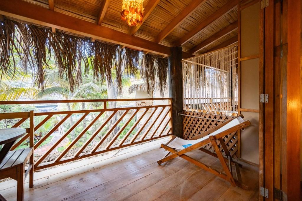 A wooden deck with a wooden bench, a hammock, and a view of greenery.