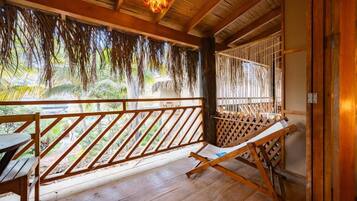 A wooden deck with a wooden bench, a hammock, and a view of greenery.