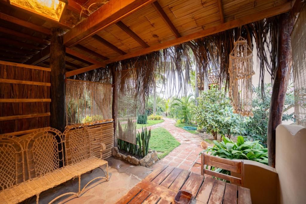 Ein Sitzbereich im Freien mit gewebten Stühlen und einem Holztisch, umgeben von einem Garten mit einem Weg und verschiedenen Pflanzen.