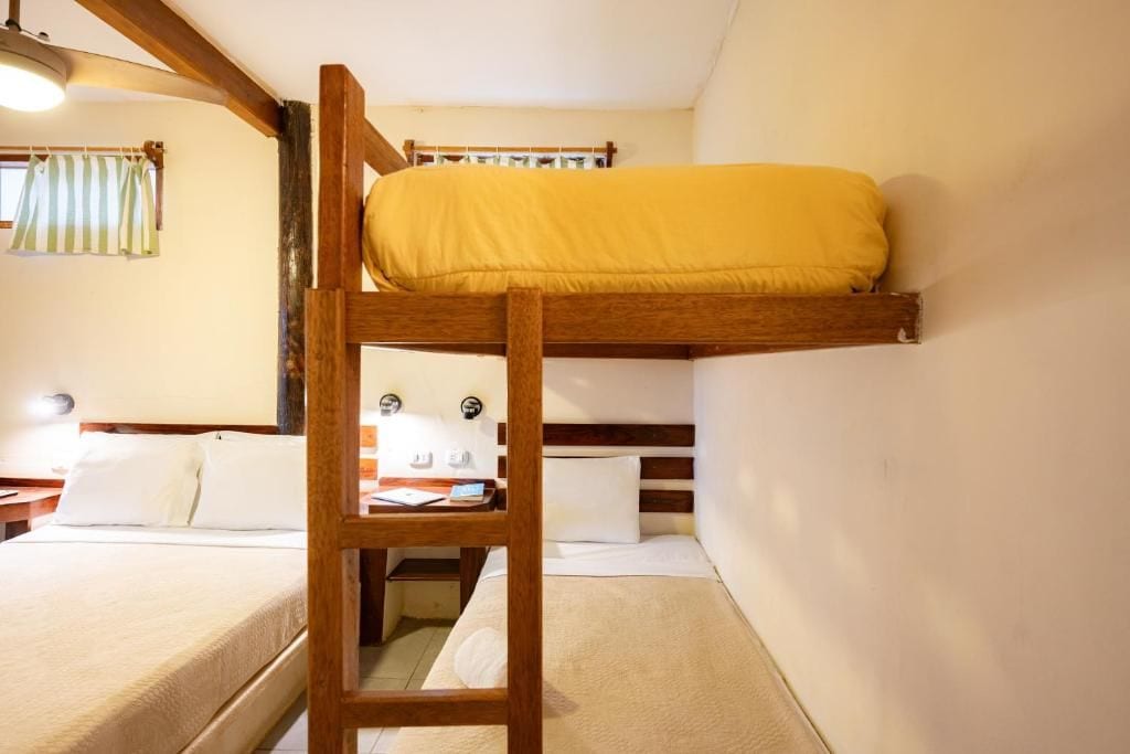 A bunk bed with a ladder, a bedside table, and a lamp.
