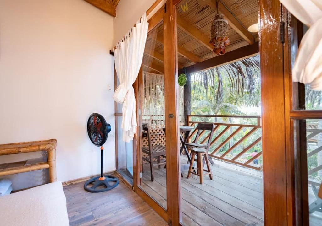 A wooden deck with outdoor furniture, a fan, and a view of the surrounding nature.