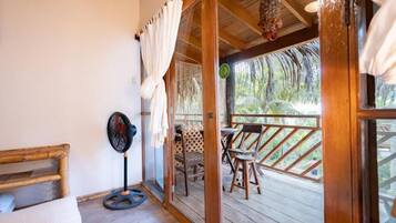A wooden deck with outdoor furniture, a fan, and a view of the surrounding nature.