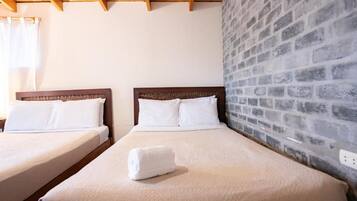 Habitación de hotel con dos camas y cabeceros de madera, junto a una pared de ladrillo.