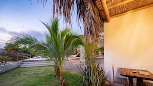 Un patio con mesa y sillas de madera, rodeado de palmeras y un sendero de ladrillo.