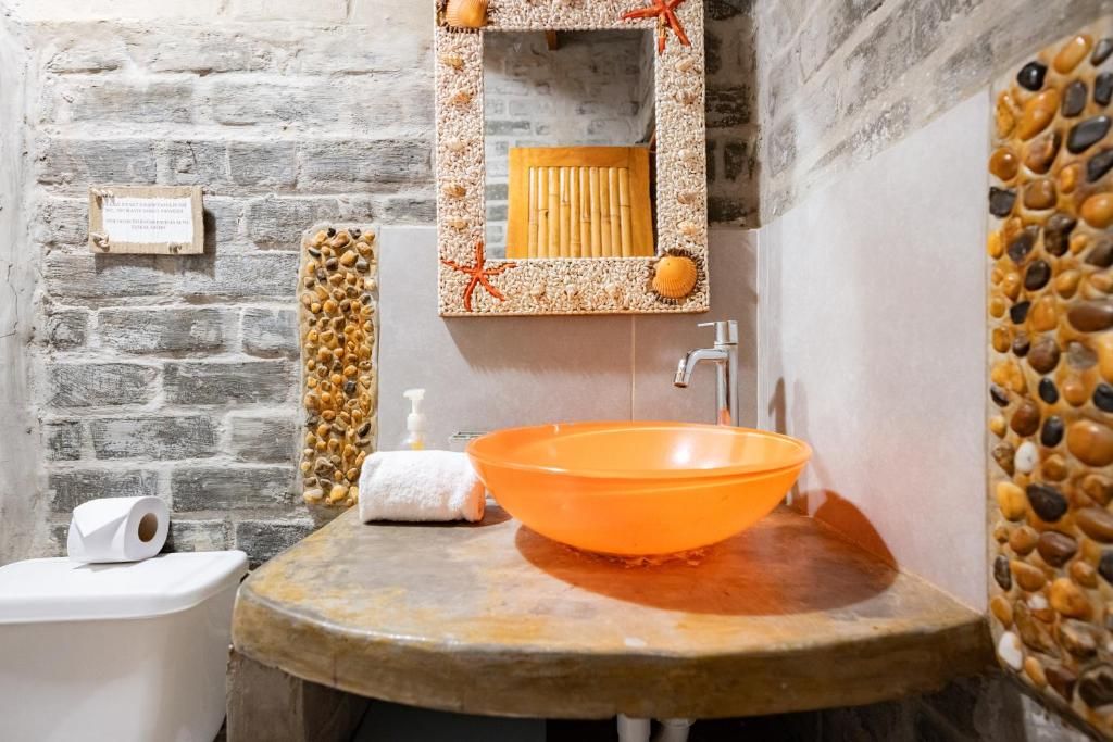 Et badeværelse med en sten vask, et spejl med dekorativ ramme og et toilet.