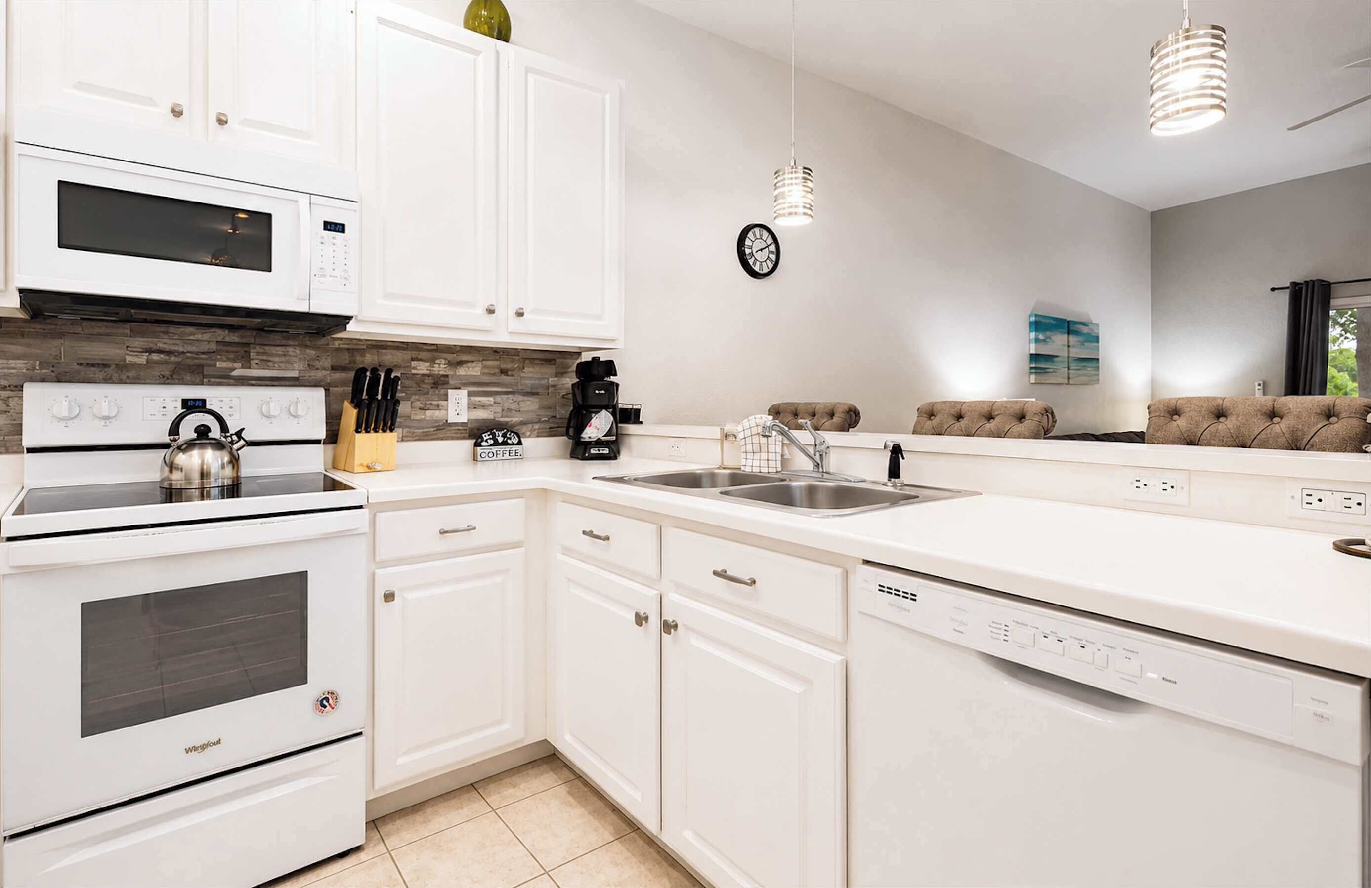 A kitchen with white cabinets, a stove, a microwave, a coffee maker, and a dishwasher.
