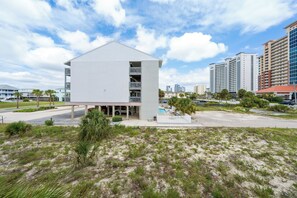 Um edifício moderno com telhado plano, várias varandas e área de piscina.