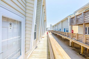 A wooden boardwalk leading to a row of beachside cabins with large windows and a clear sky. - Gulf View 8 (Gulf Shores)