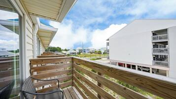 A wooden deck with a chair, overlooking a residential area with houses and a clear sky.