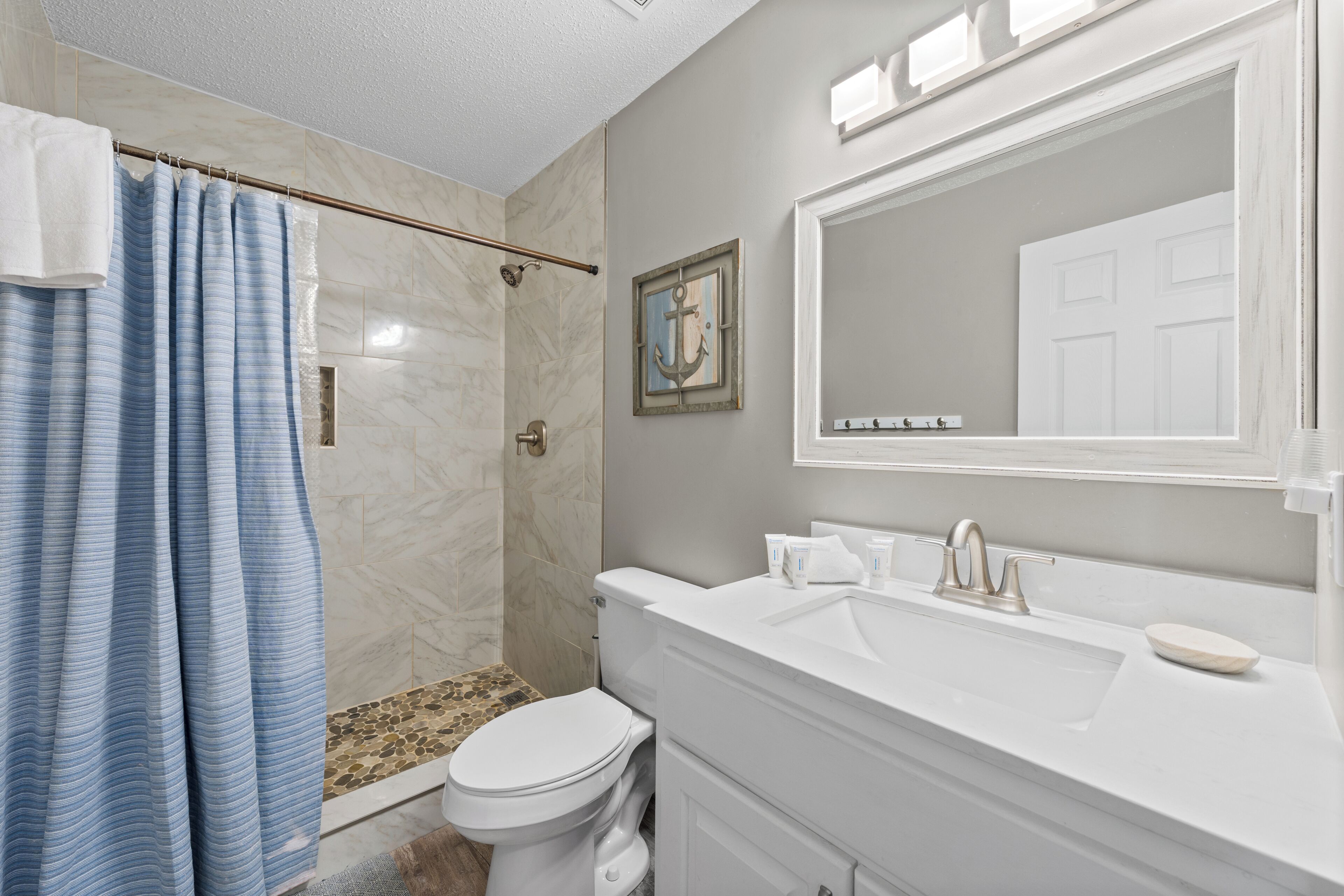 Une salle de bain avec douche, toilettes et lavabo.