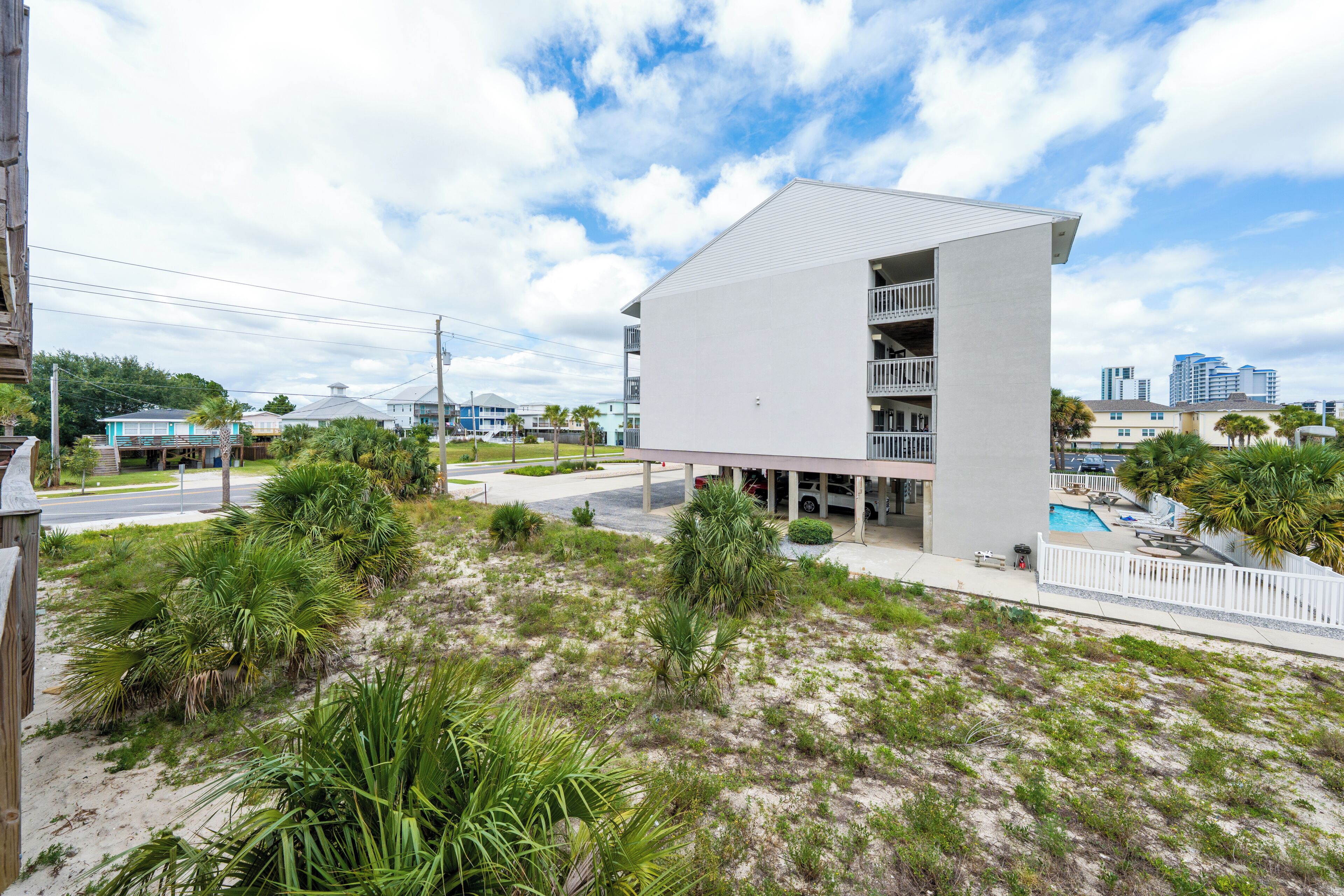 A modern building with a flat roof, multiple balconies, and a pool area with a white fence.