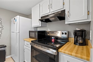 A compact kitchen with a refrigerator, microwave, stove, oven, and a coffee maker. - Gulf View 8 (Gulf Shores)