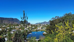 Un pueblo costero con un lago central, rodeado de edificios residenciales y montañas.