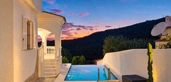 Un espace piscine offrant une vue sur une colline et le coucher de soleil.