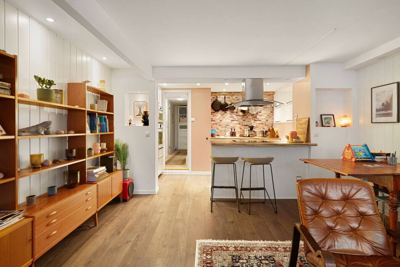 A modern kitchen with wooden cabinets, a central island, and bar stools.