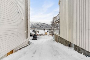 A narrow snow-covered alleyway between buildings with a car parked at the end. - Fogd Drejers Gate – Tromsø City Centre (Tromsø)