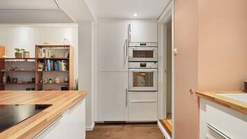 A modern kitchen with white cabinetry, a wooden countertop, and a built-in oven.