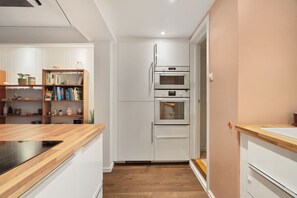 Una cocina moderna con armarios blancos, una encimera de madera y un horno empotrado.